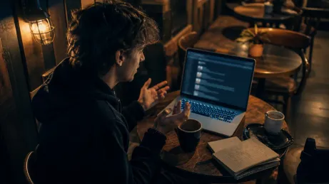 A user at a café discussing Onion Browser tips with a laptop and notes.